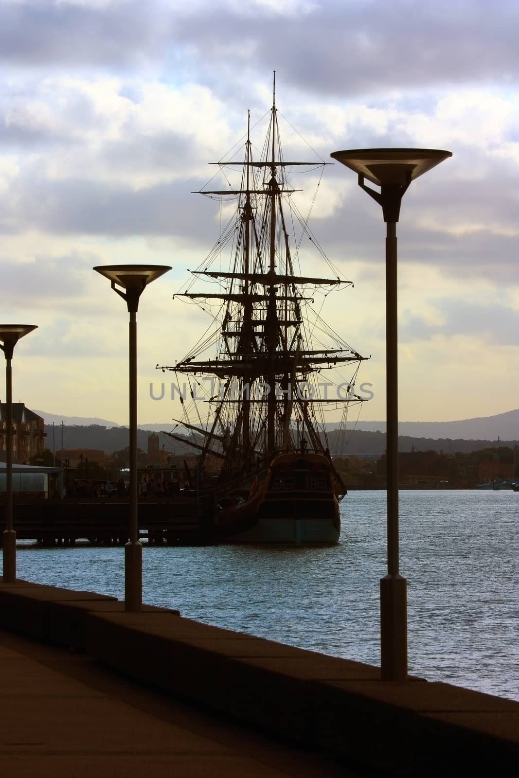 An old sailing ship moored at a pier by definitearts