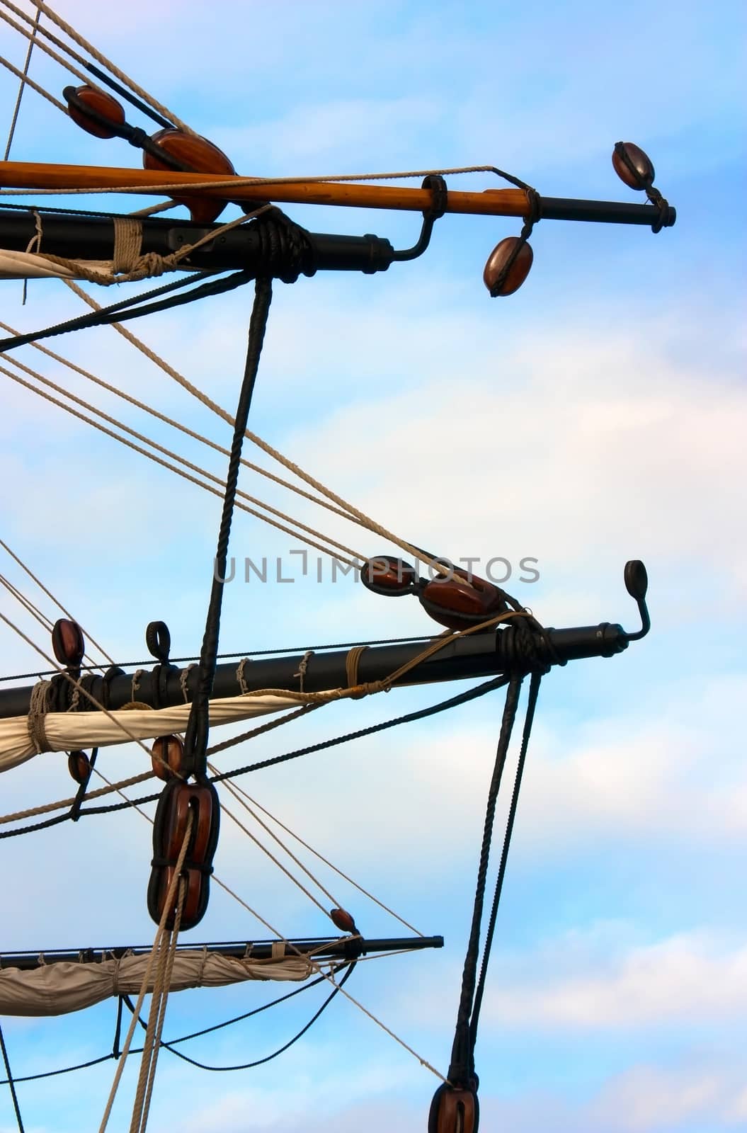 Spars and pulley blocks of an old sailing ship against sky background