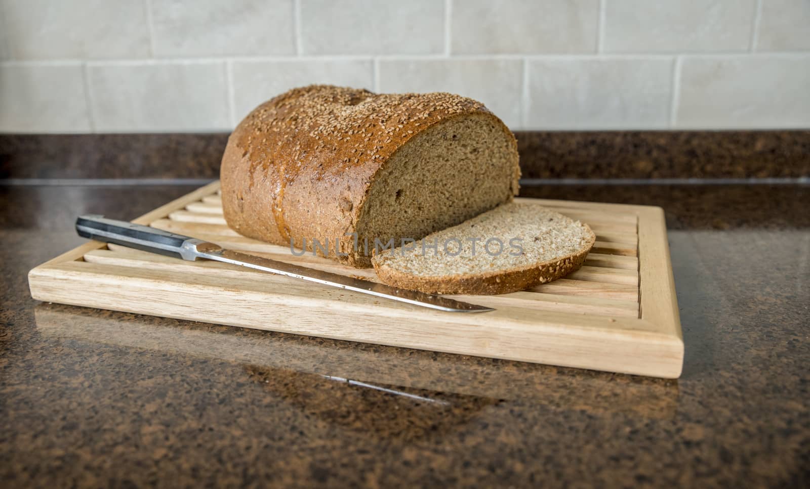 freshly baked bread with a cut slice with a kitchen knife on a wooden plant in the kitchen