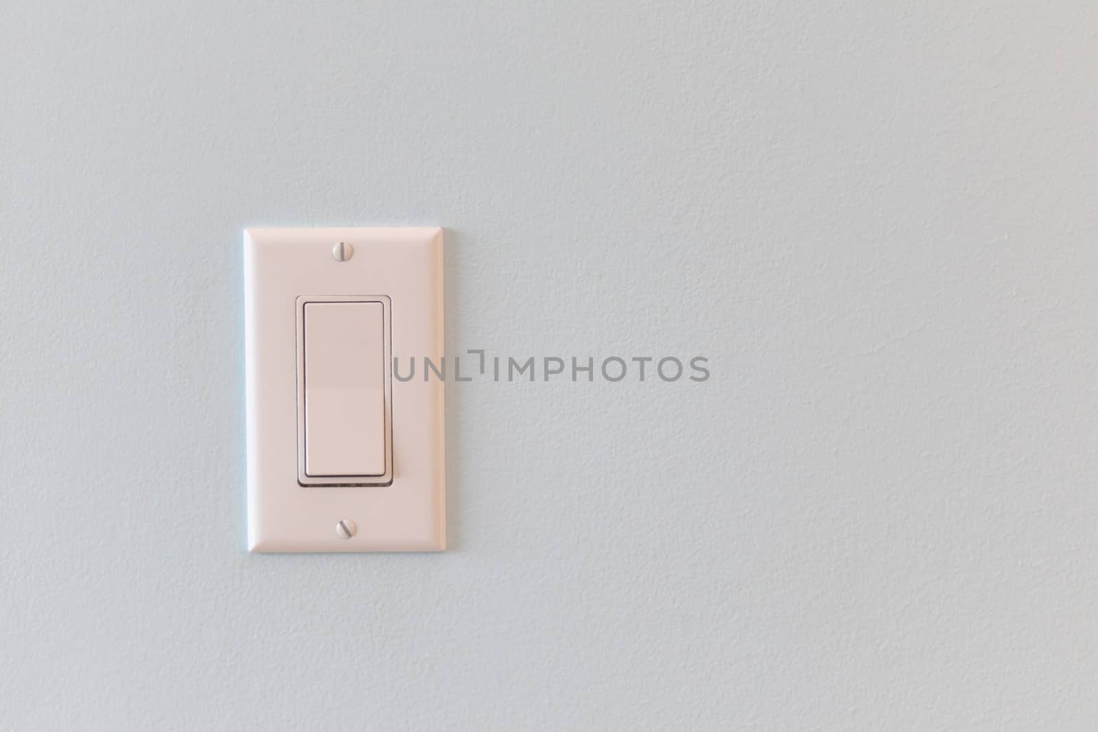 A light switch with a flat panel rocker design is on a wall in a house.