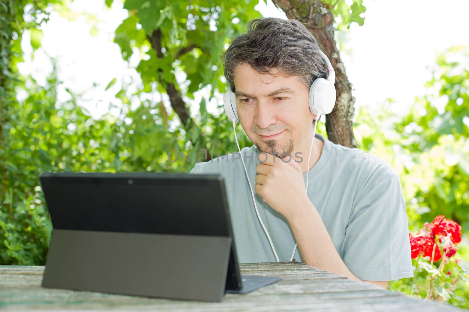 young man relaxing with a tablet pc listening music with headphones on a the park, outdoor