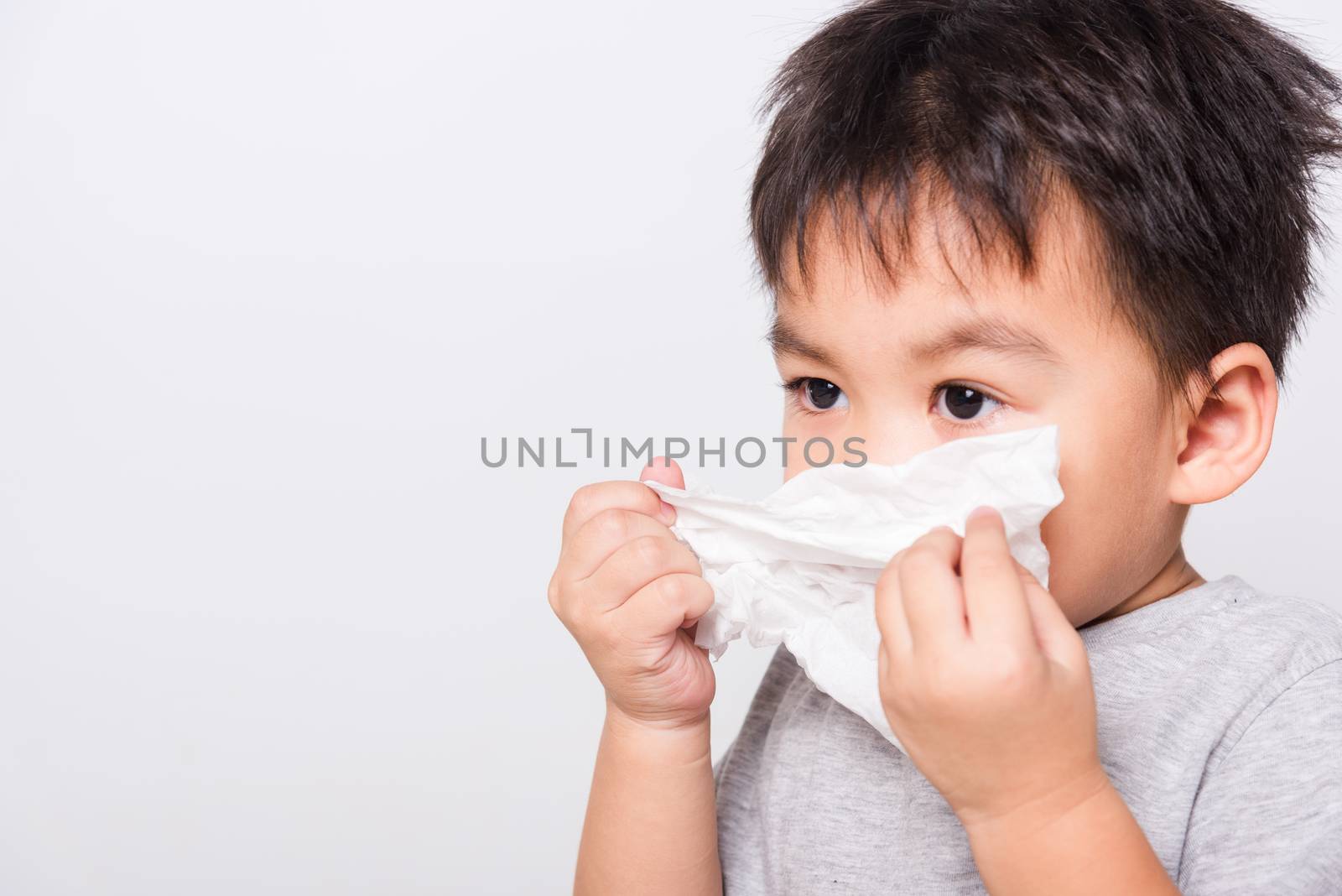 Closeup Asian face, Little children boy cleaning nose with tissue on white background with copy space, health medical care