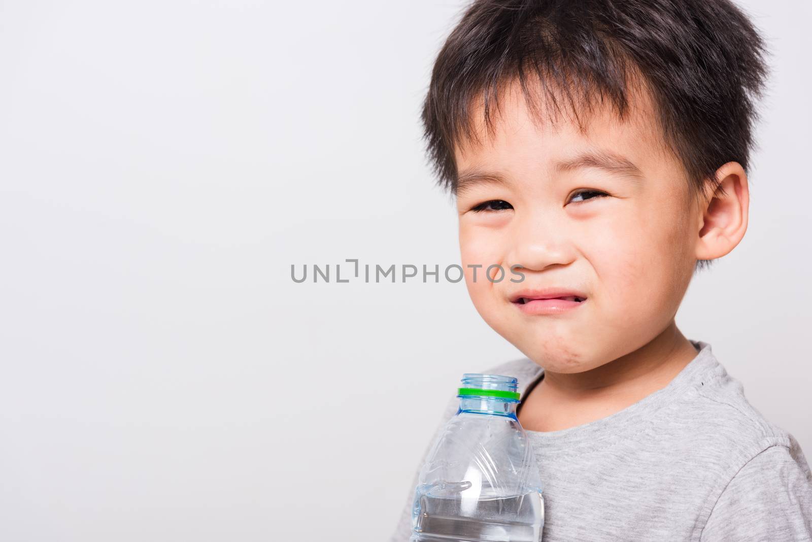 Closeup Asian face, Little children boy drinking water from Plastic bottle on white background with copy space, health medical care