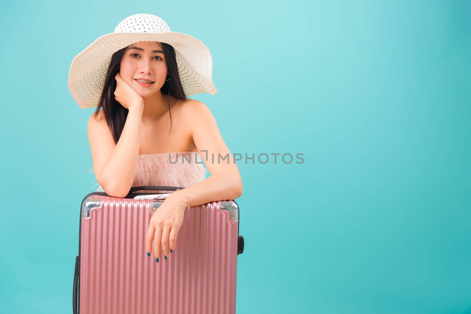Portrait asian beautiful woman with hat her sitting with travel bag on weekends on blue background, with copy space for text
