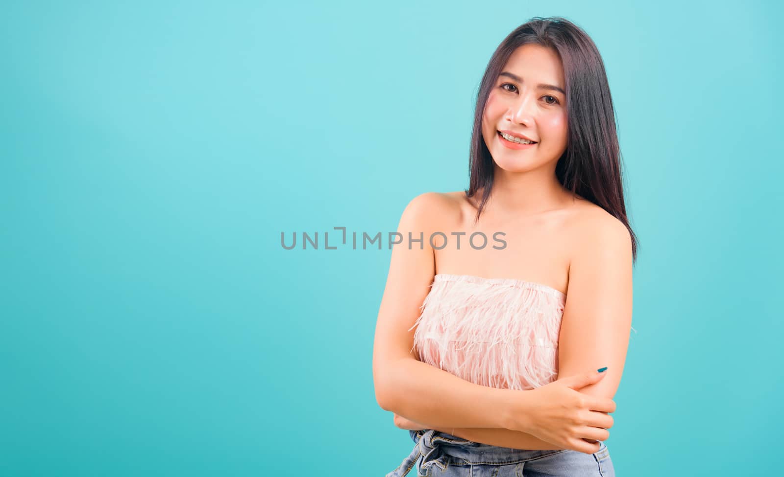 Smiling face Asian beautiful woman her cross arm looking to camera on blue background, with copy space for text