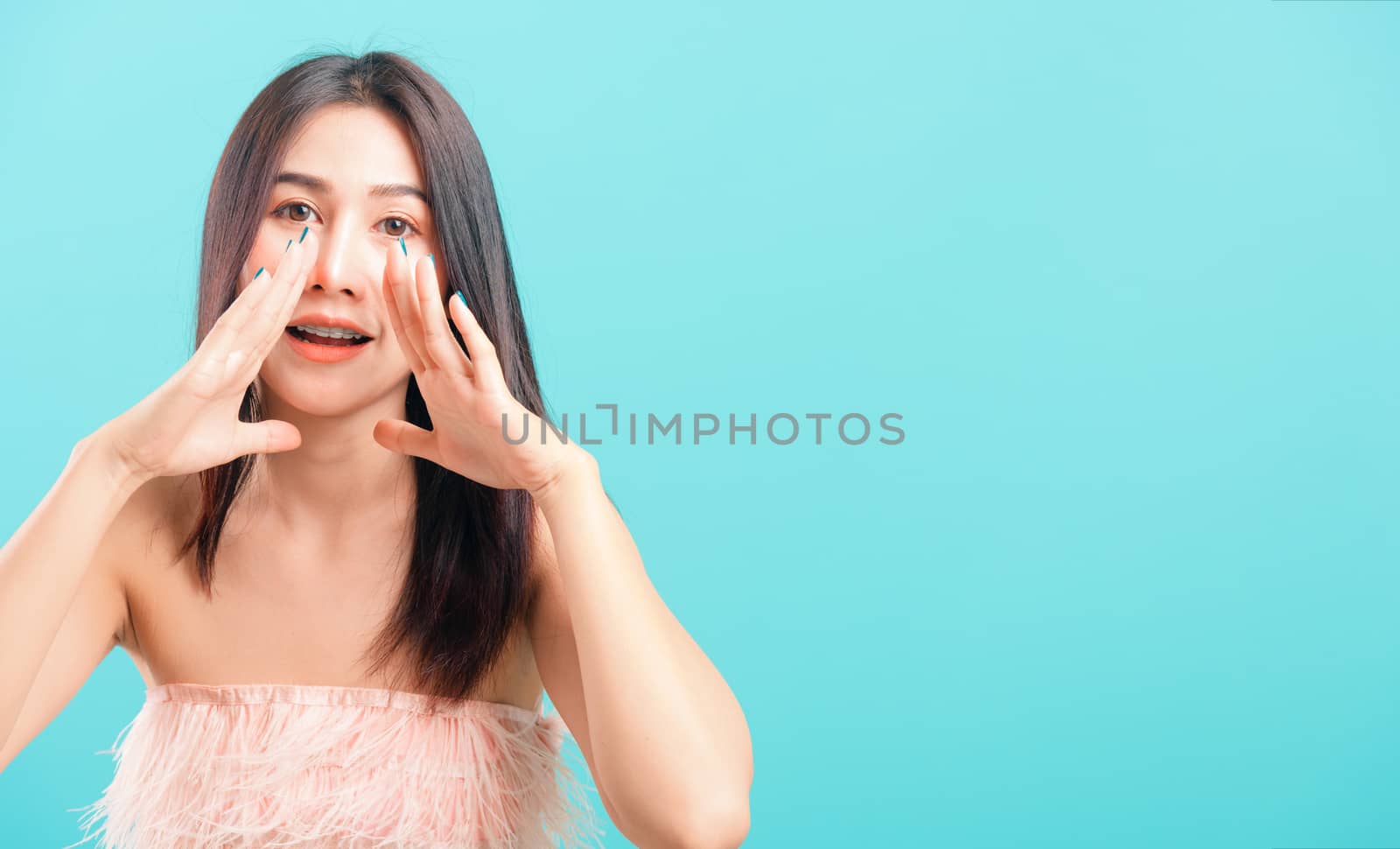 Portrait asian beautiful woman smiling her standing big shout out with hands next mouth on blue background, with copy space for text