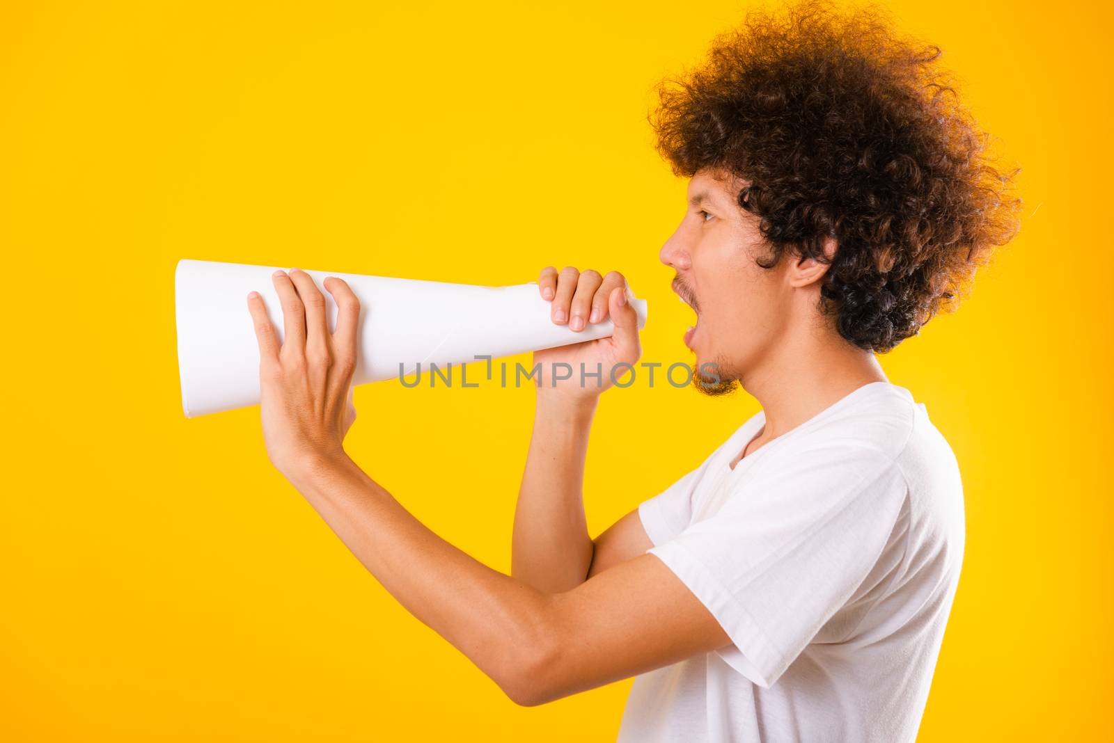 Asian handsome man with curly hair he announcing or spreading news using white speaker paper isolate on yellow background