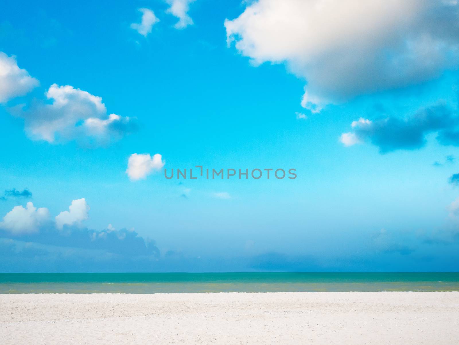 White sand beach with bright blue sky and cloud over sea.