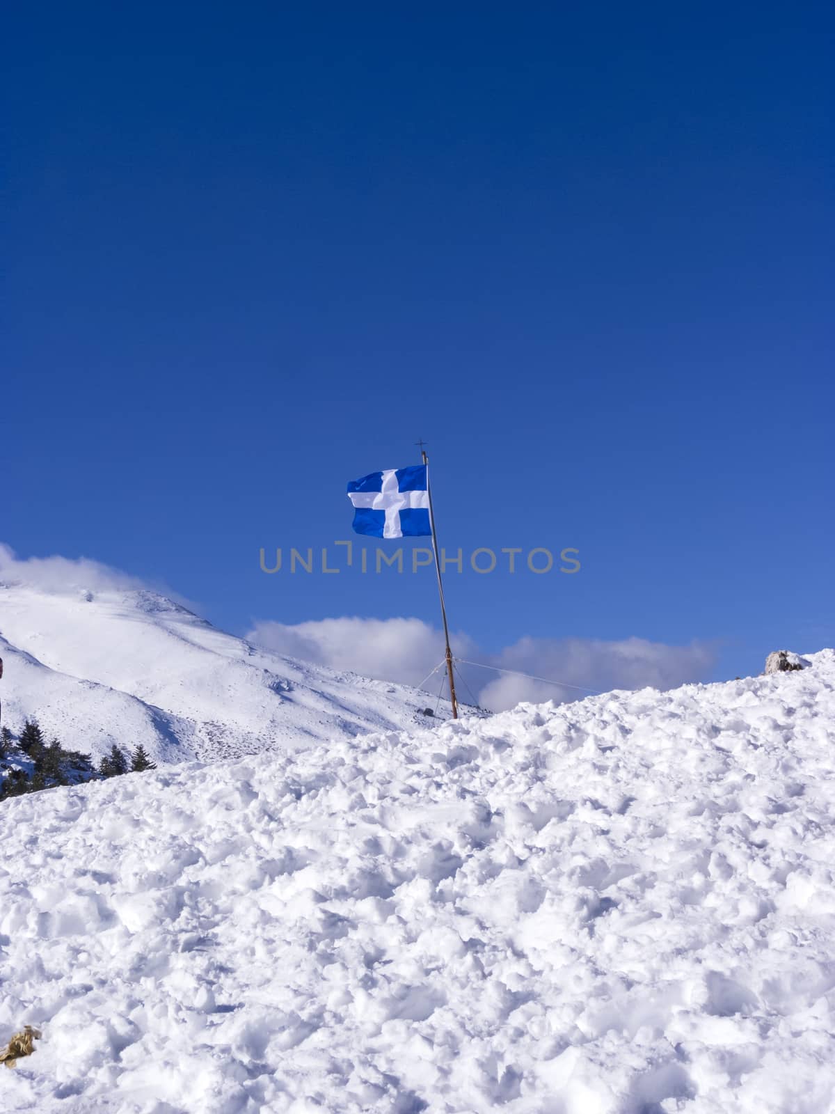 Greek flag at Ziria mountain covered with snow on a winter day, South Peloponnese, Greece by ankarb