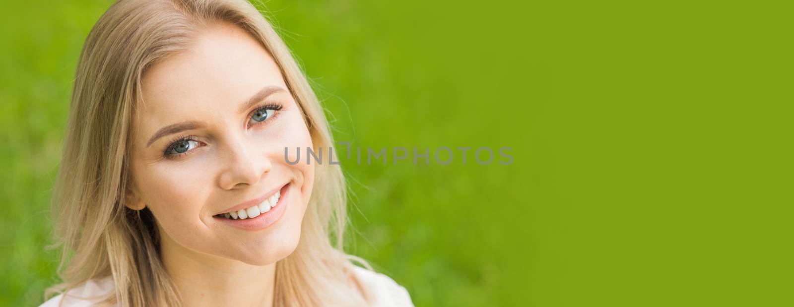 Beautiful woman portrait on spring grass meadow copy space