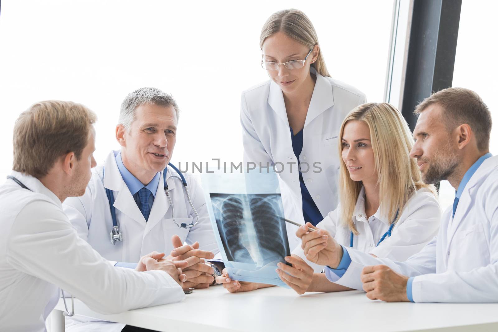 Team of experts doctors examining X-ray report on hospital office meeting