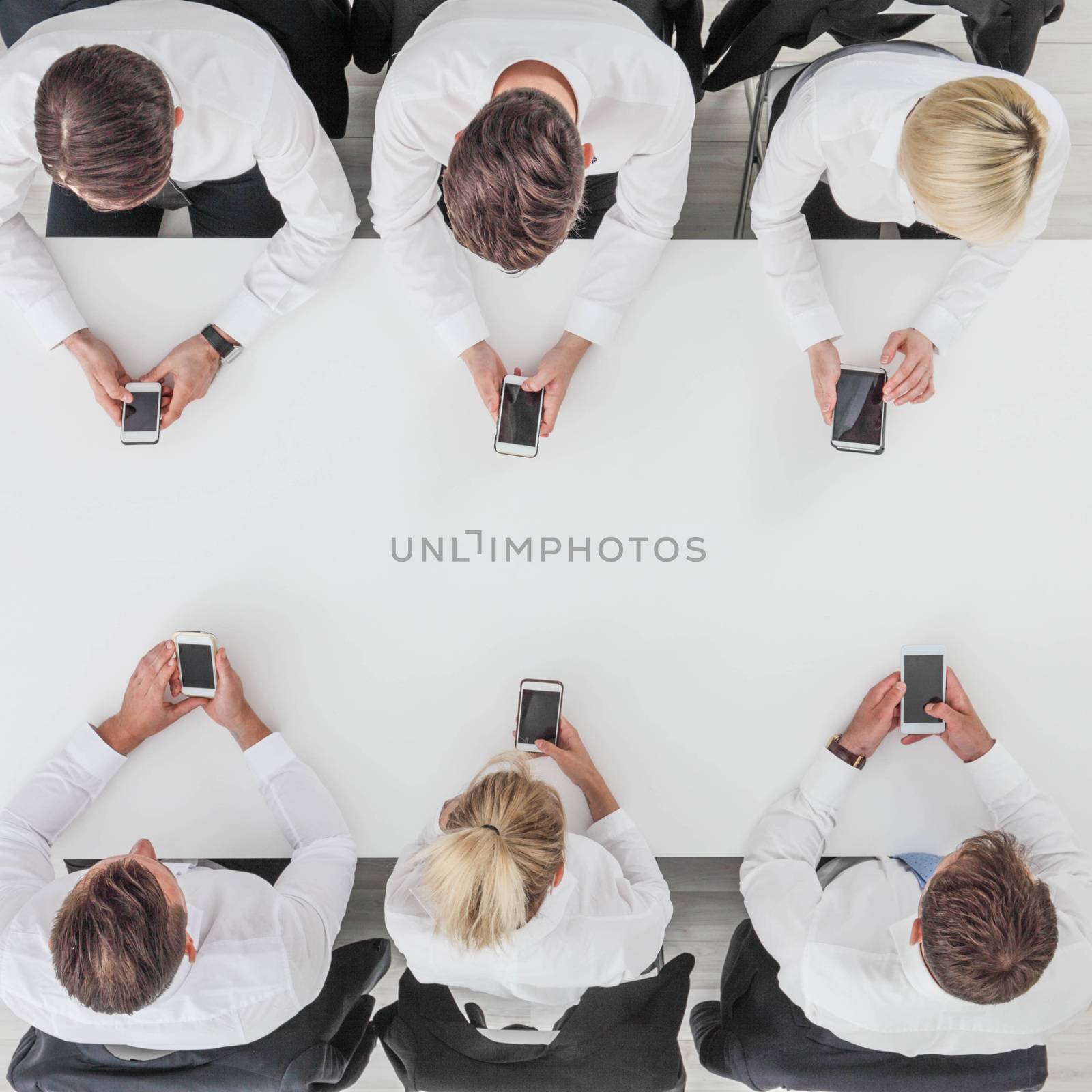 Business people using smartphones sitting at table in office, white copy space background