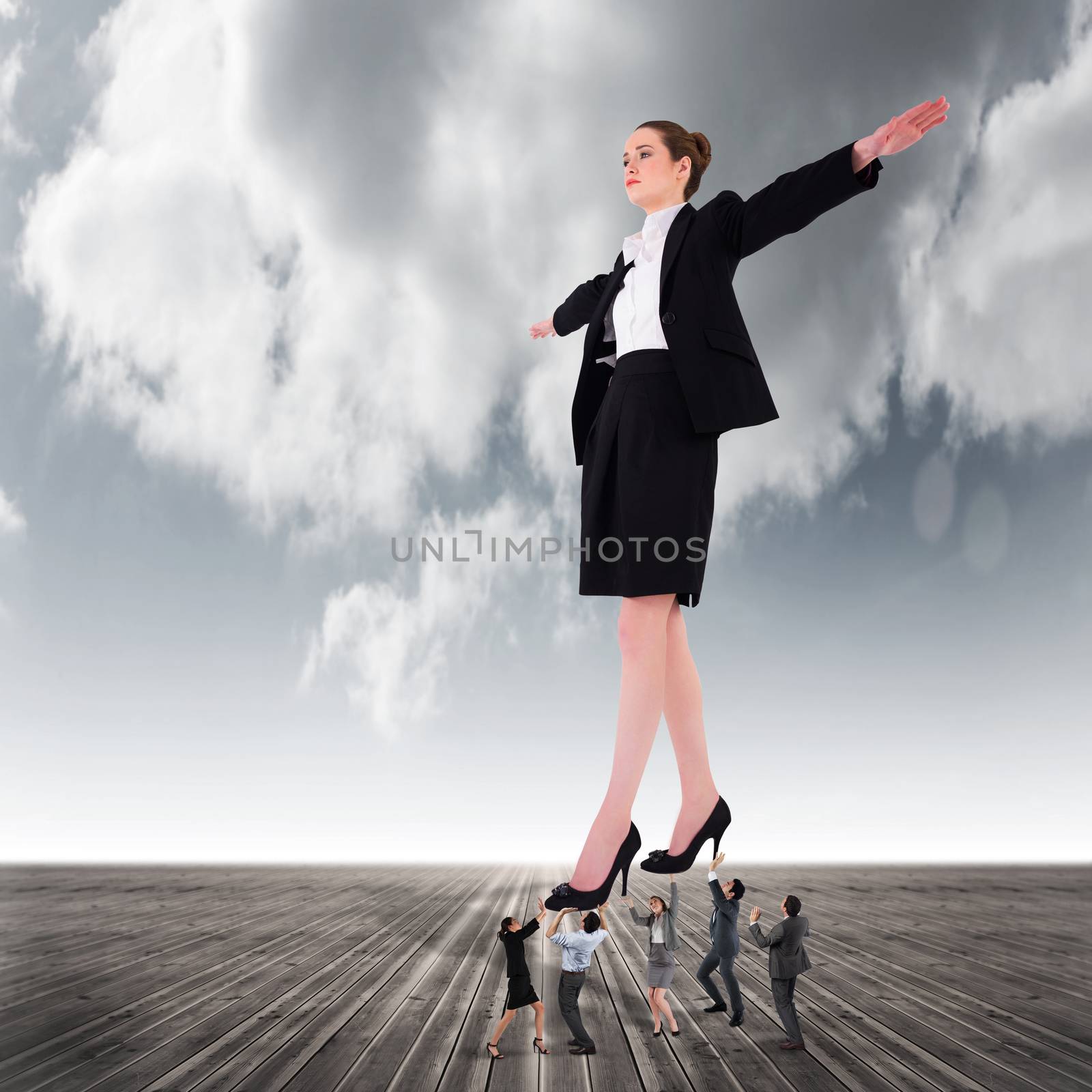 Composite image of business team supporting boss against cloudy sky background
