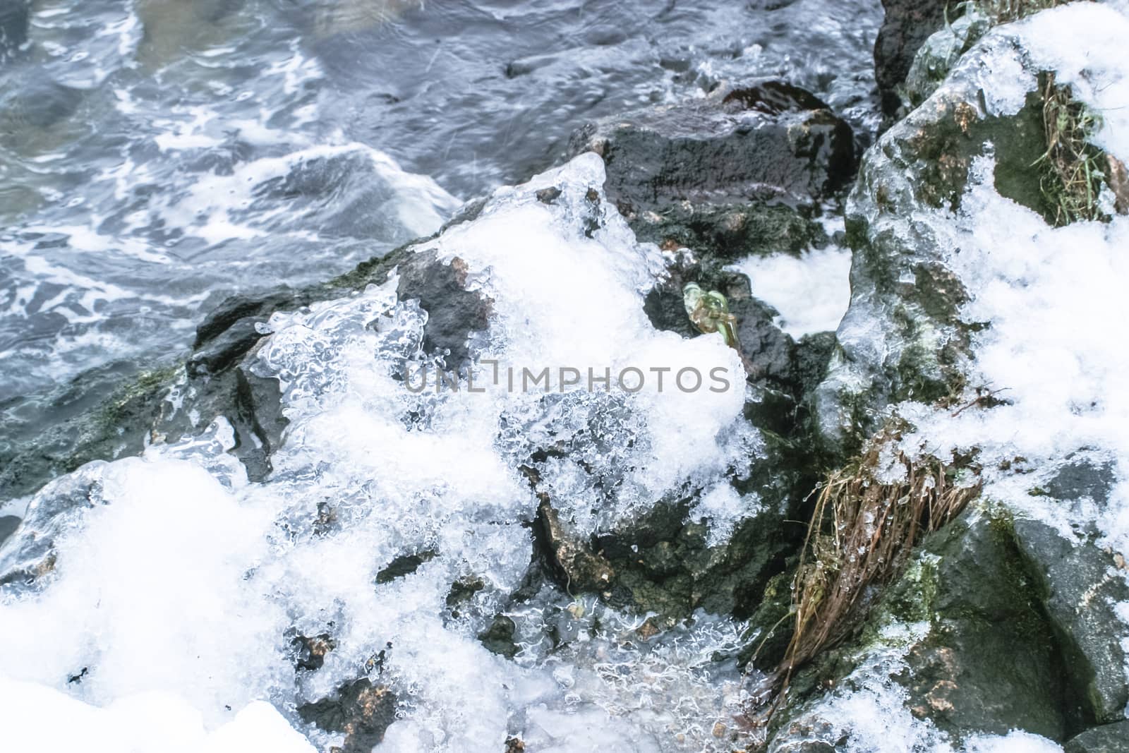 Cliff Shore of the river with waves and ruffles water in a winter frosty weather. River shore with snow in winter