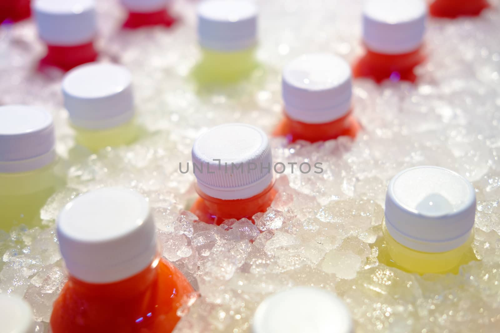 Close-up of Fresh juice of different exotic fruits bottles on the ice box. Mix of plastic bottles on the ice bucket for sale in food market. 