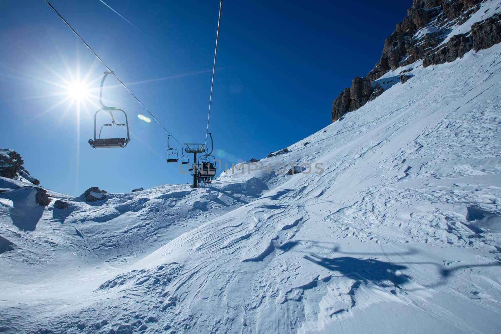 Ski lift chairs on bright winter day by destillat