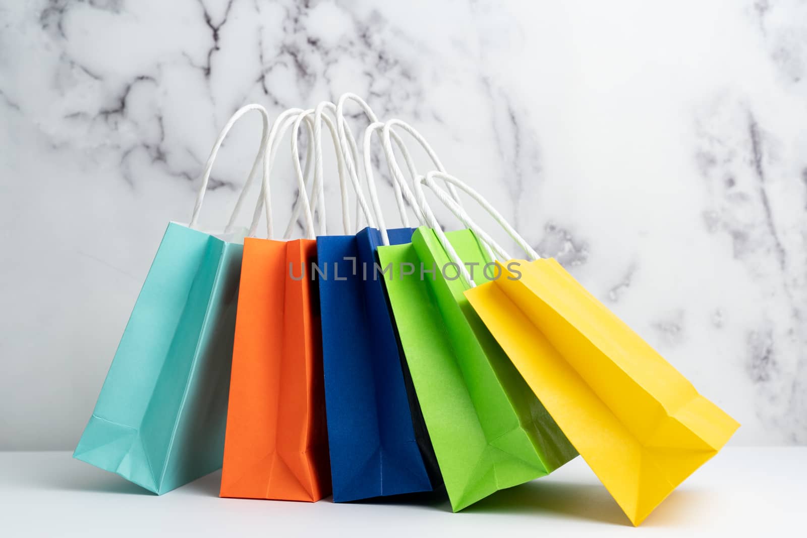 Five colorful gift or shopping bags against marble background