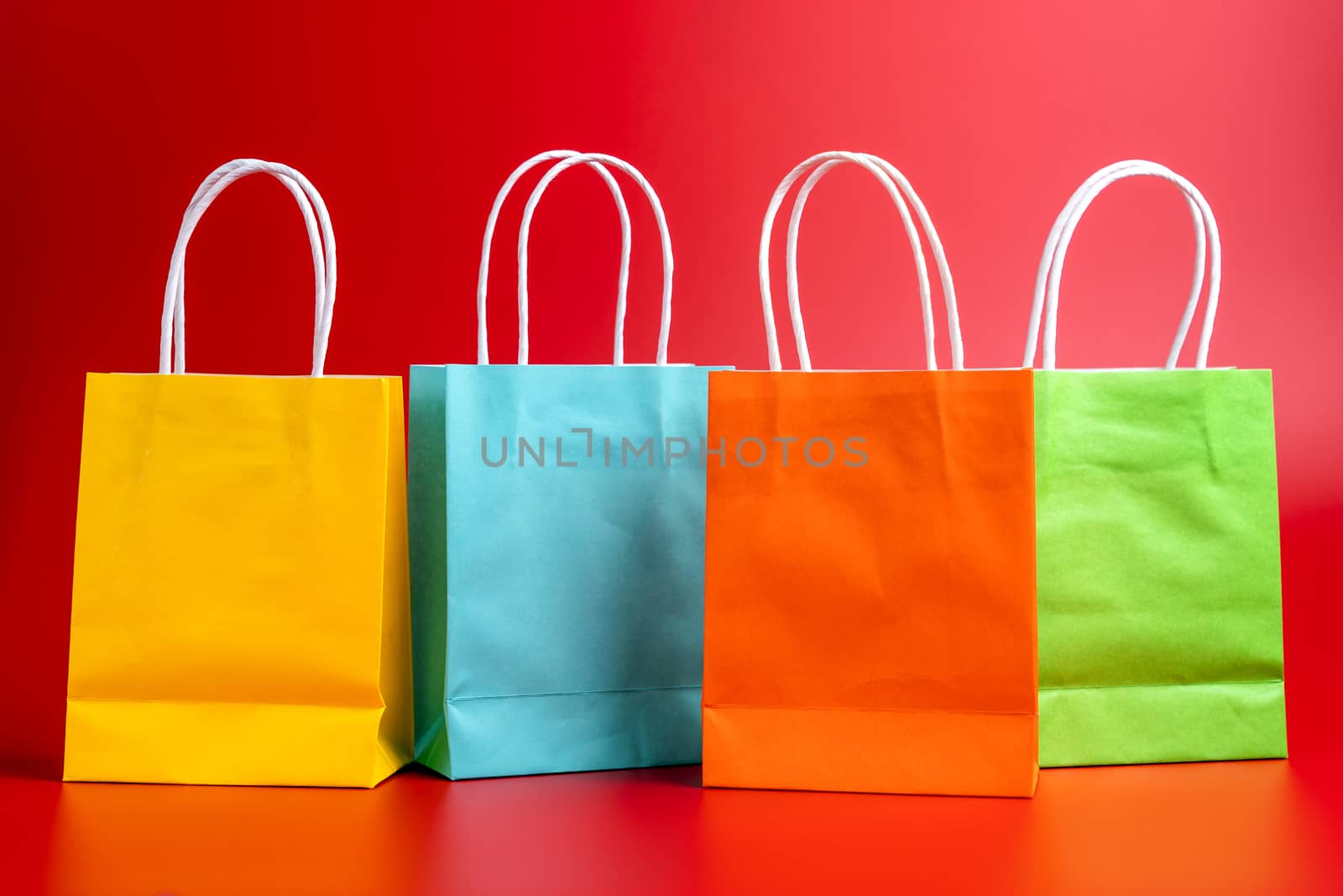 Four colorful gift or shopping bags isolated on red background