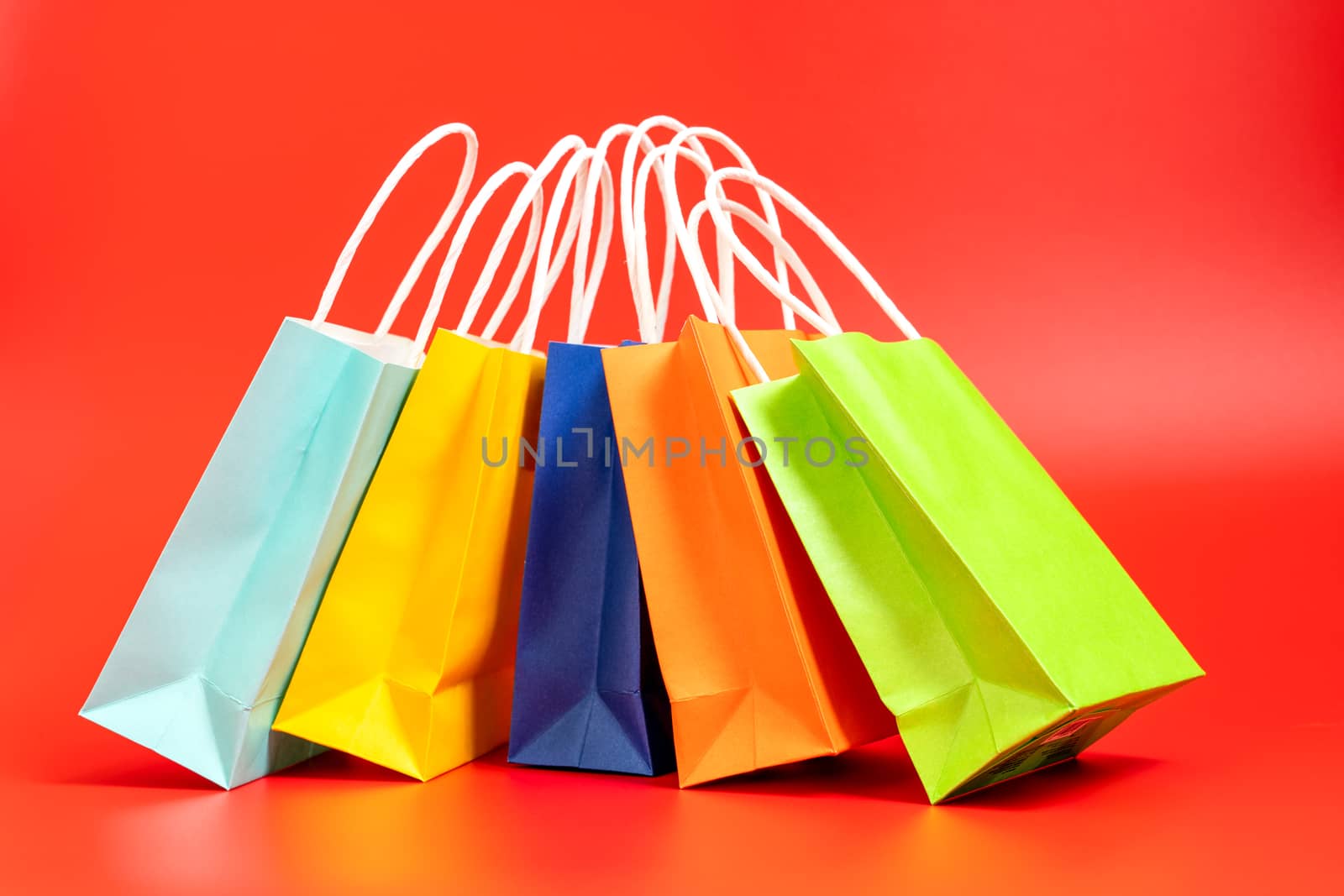 Five colorful gift or shopping bags isolated on red background