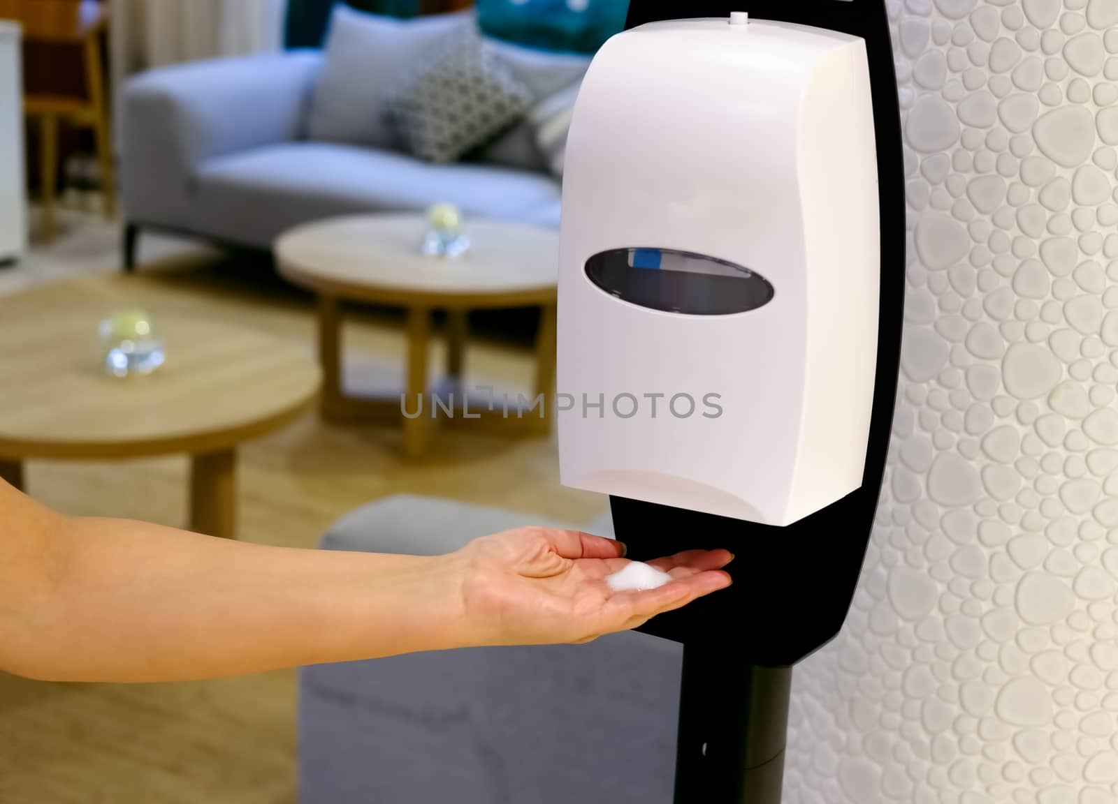 Closeup of Hands under the automatic alcohol dispenser. Sanitation station for cleaning of hands.  Infection prevention concept. Save and clean in public medical center area.  