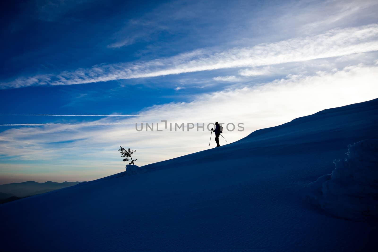 Hiker silhouette at dawn on Mount Ciucas trail in winter, part of Romanian Carpathian Range