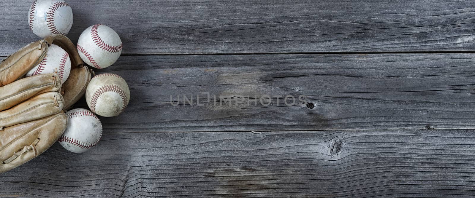 Old used baseballs and weathered glove on vintage wooden background. Baseball sports concept with copy space
