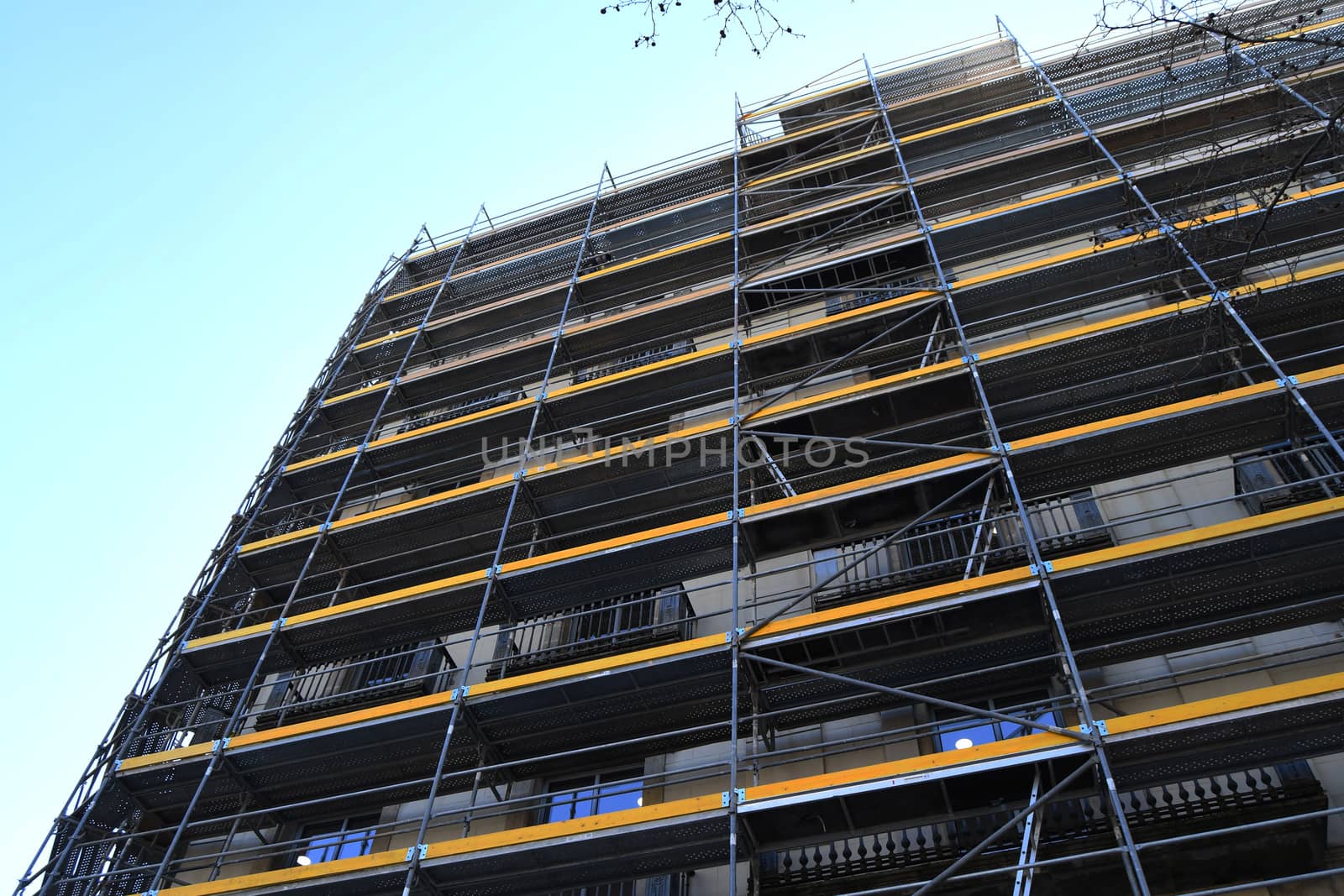 Yellow scaffolding of a building under restoration on a clear sunny day in Barcelona