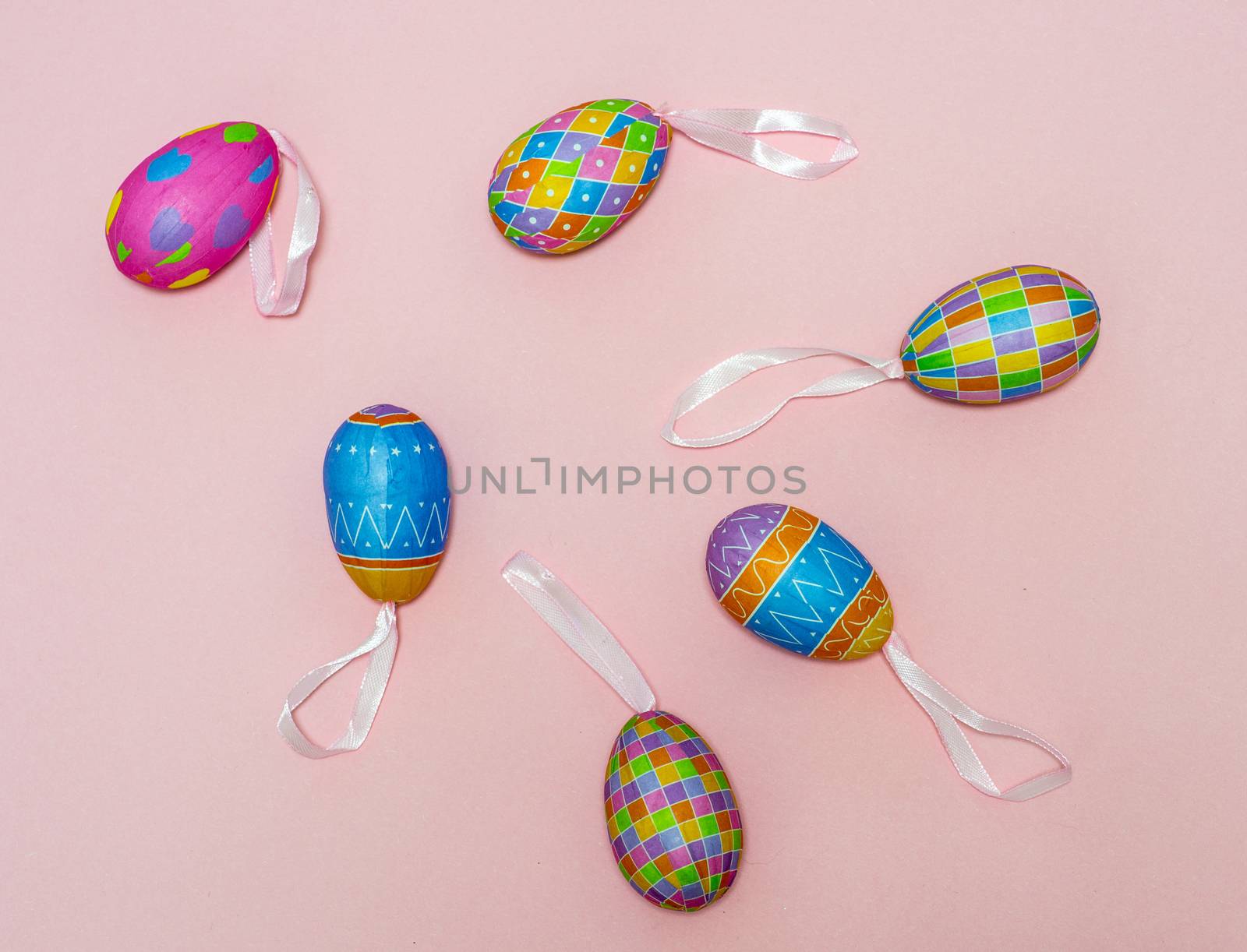 Paper colorful Easter eggs lie on a gently pink background. Easter concept