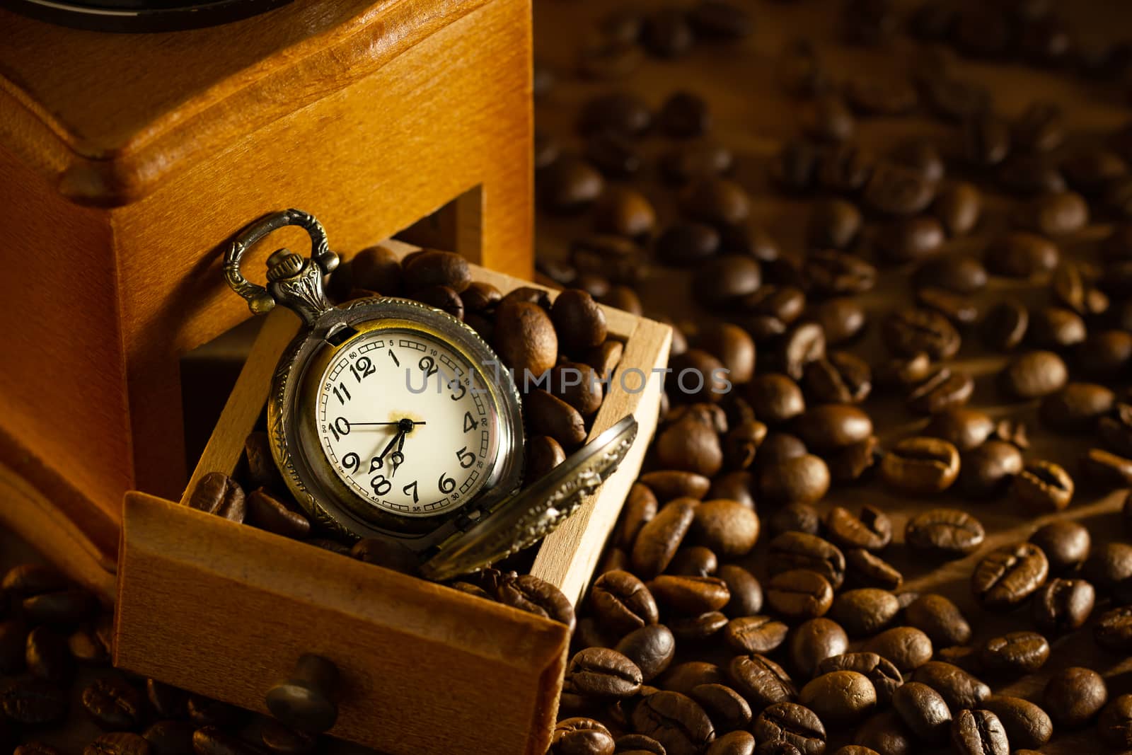 Coffee bean and pocket watch the tray of manual grinder on table by SaitanSainam