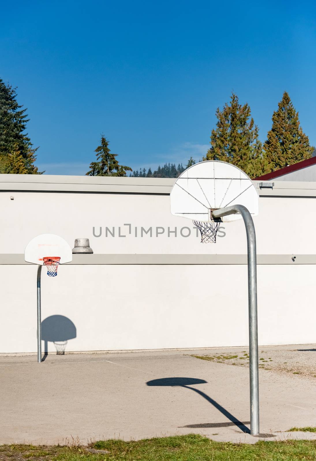 Basketball court with two baskets on school back yard by Imagenet