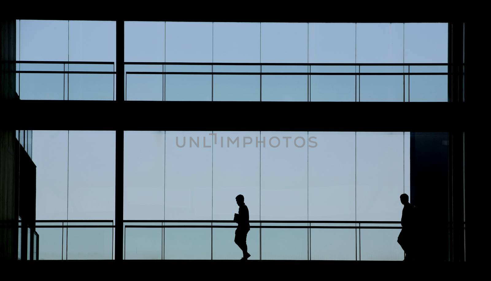 Silhouette view of two people in a modern office building interior with panoramic windows.