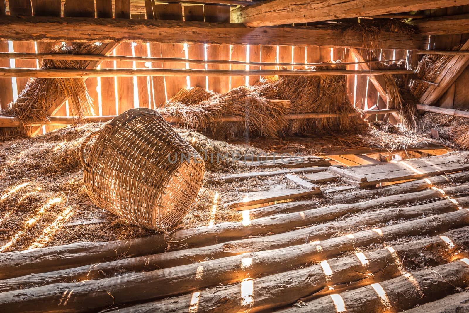 Early morning sunlight streams into a rustic barn on broken basket nex to pile of hay. Nice rustic vintage concept. by petrsvoboda91