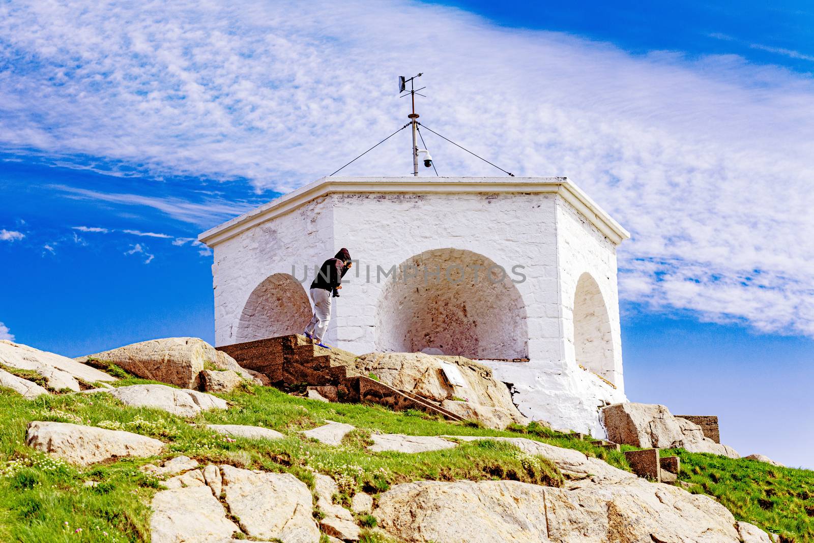 Historic white lighthouse on the edge of rocky sea coast,  Lindesnes, South Norway