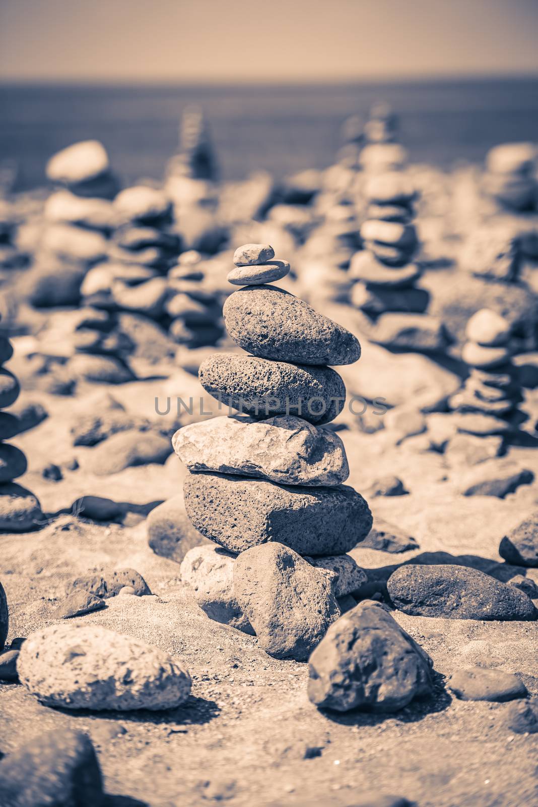Pyramid of stones in the sand at the beach. Stylized picture.