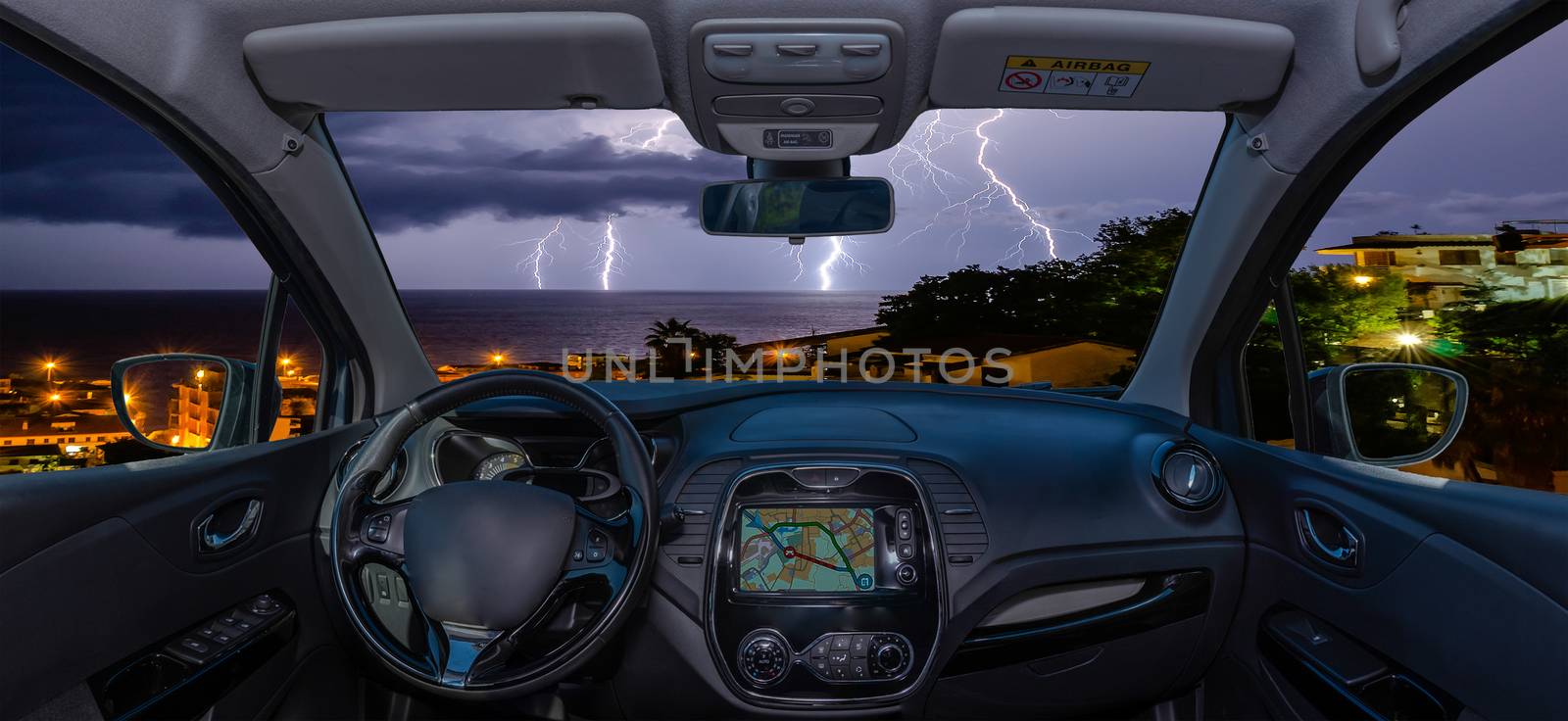 Looking through a car windshield with view over lightning storm over the sea
