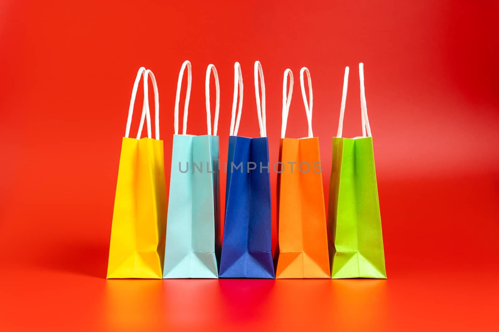 Five colorful gift or shopping bags isolated on red background