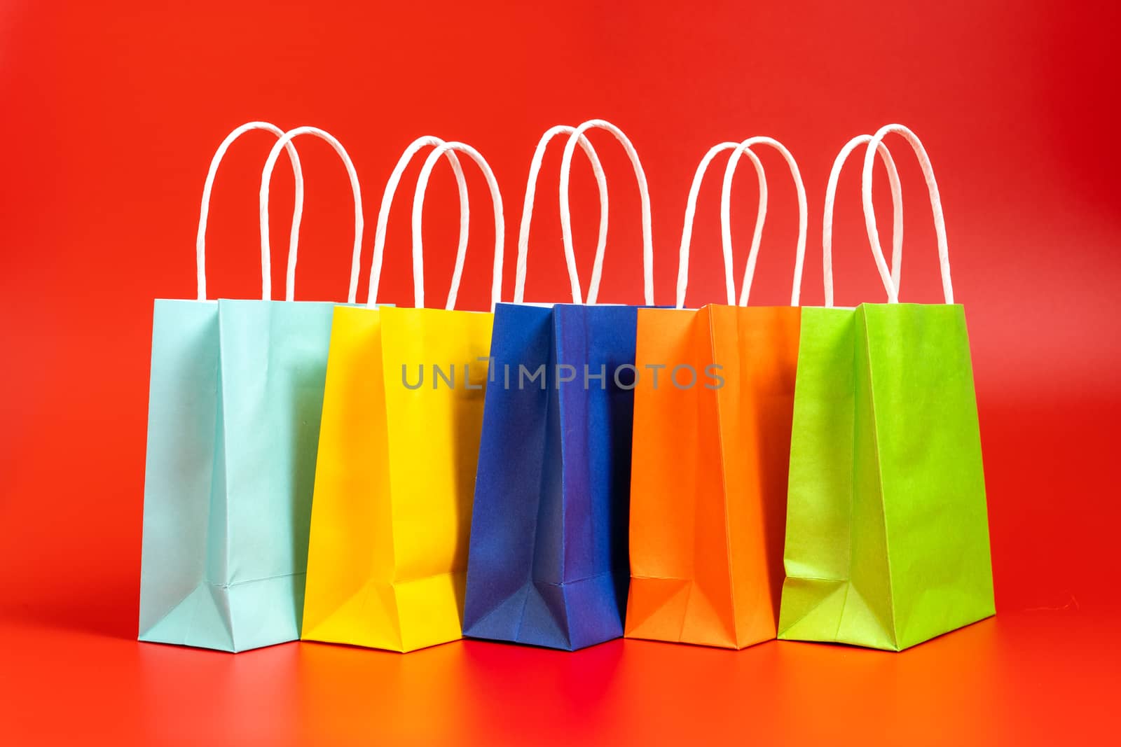 Five colorful gift or shopping bags isolated on red background