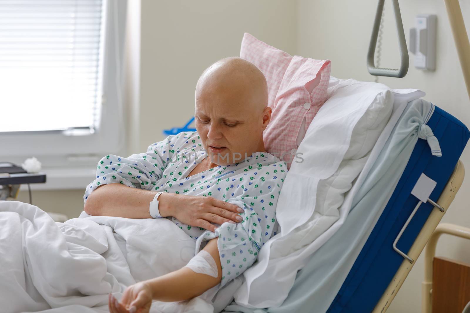 Middle age woman without hair after chemotherapy patient lying at hospital bed feeling sad and depressed worried. Disease feeling sick in health care and clinical attention concept.