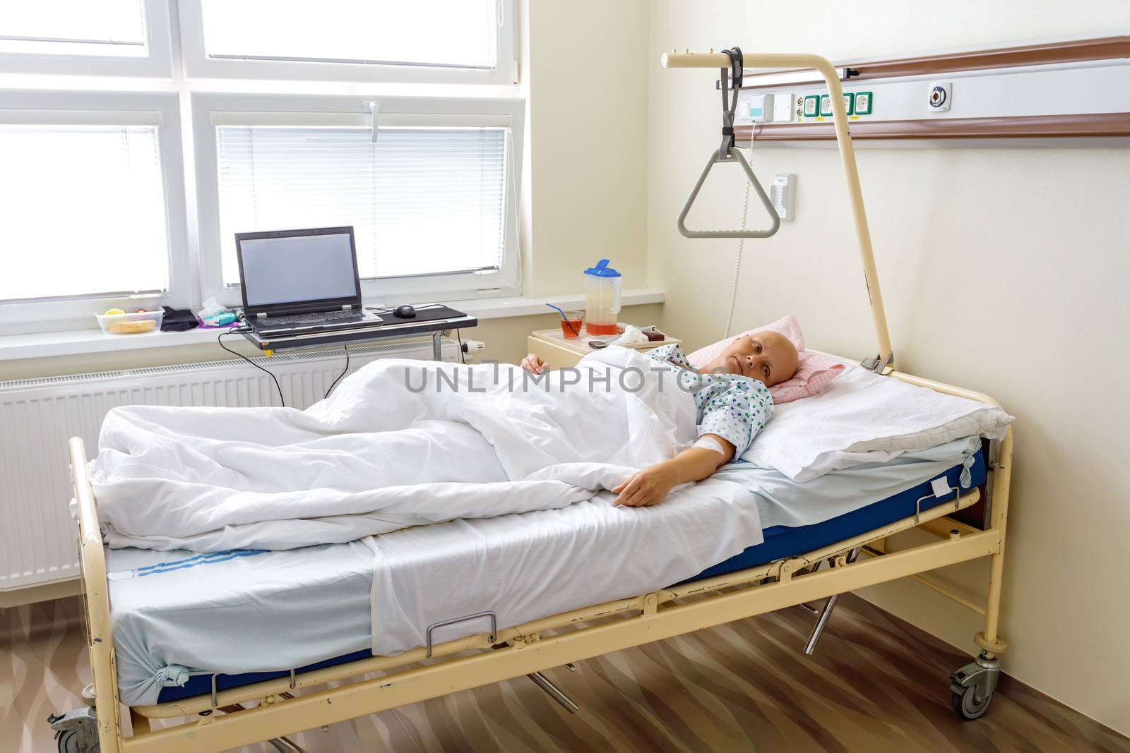 Middle age woman without hair after chemotherapy patient lying at hospital bed feeling sad and depressed worried. Disease feeling sick in health care and clinical attention concept.