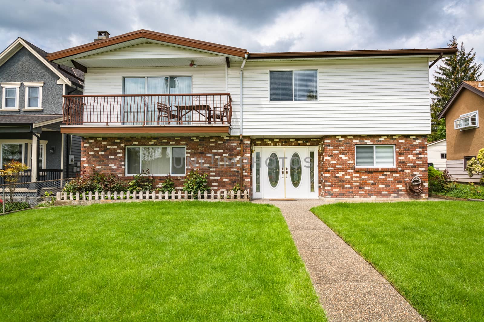 Average residential house from 1970th with big green lawn in front. by Imagenet