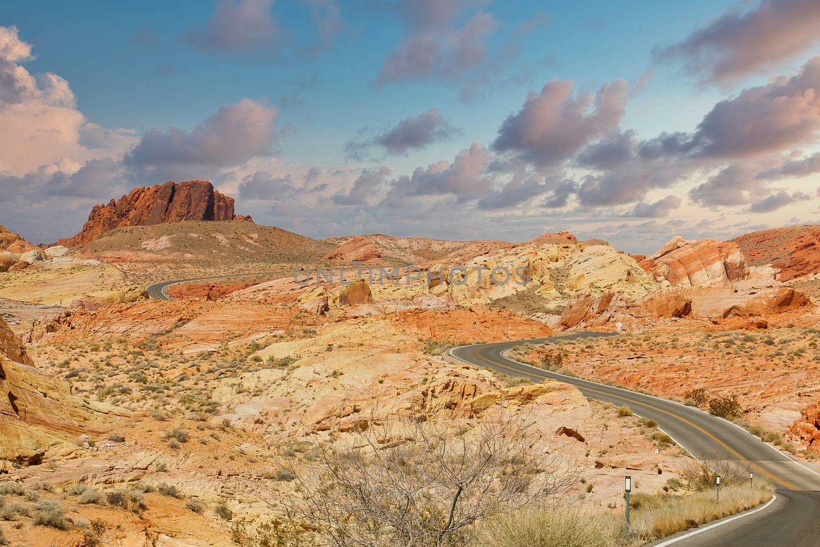 A two lane road winding through the desert near red rocks