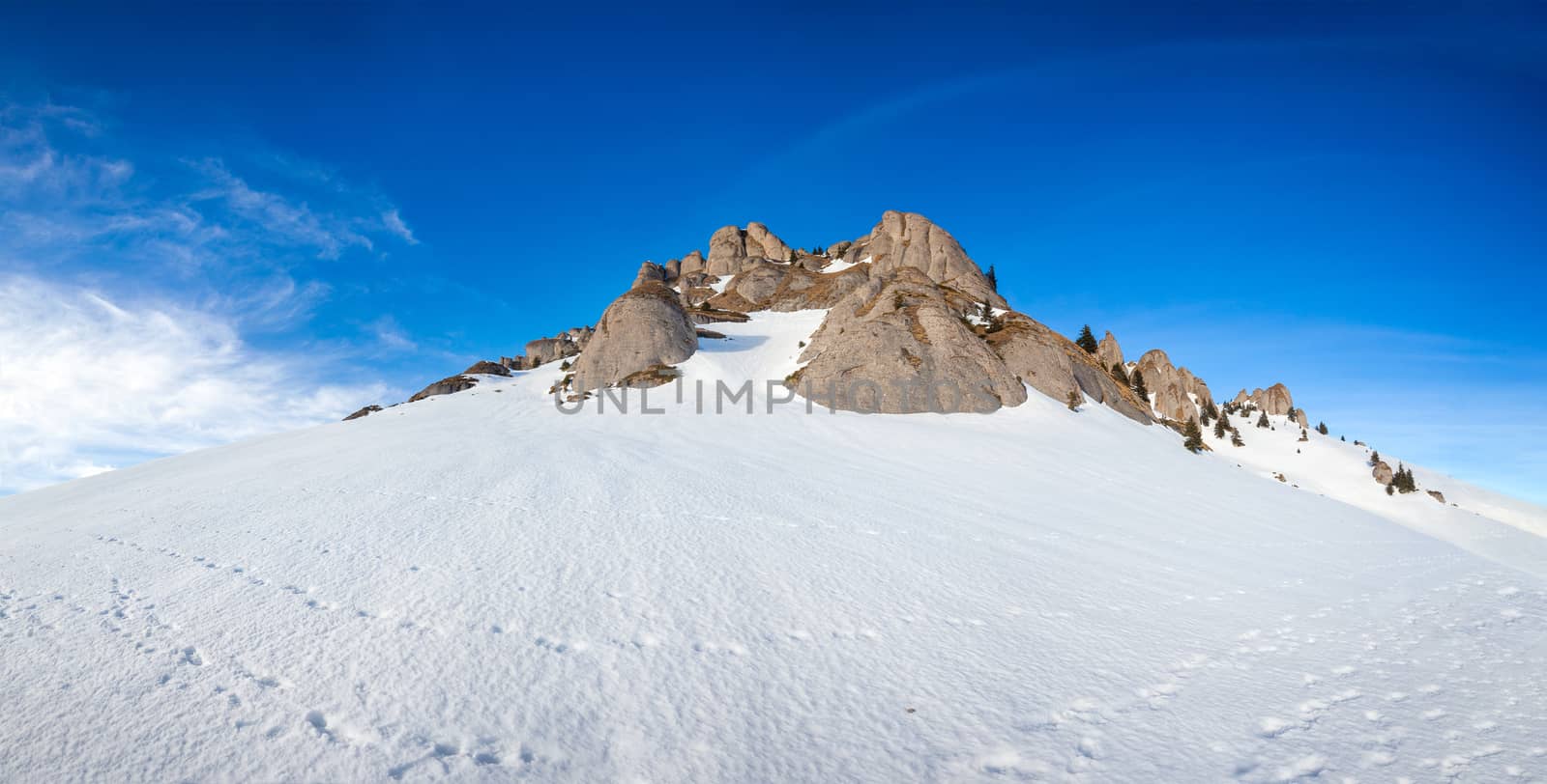 Panoramic view of Mount Ciucas peak covered in snow at sunset on winter, part of Romanian Carpathian Range