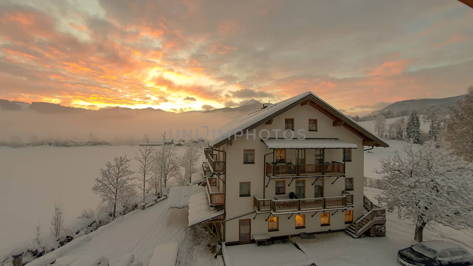 Sunrise over Snowy Mountains With German looking Building against a red and Yellow Sky by TheDutchcowboy