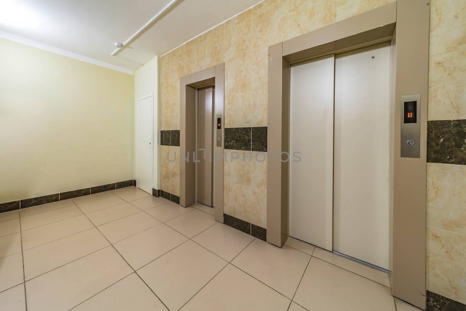 empty modern elevator or lift with closed metal doors brown tile design