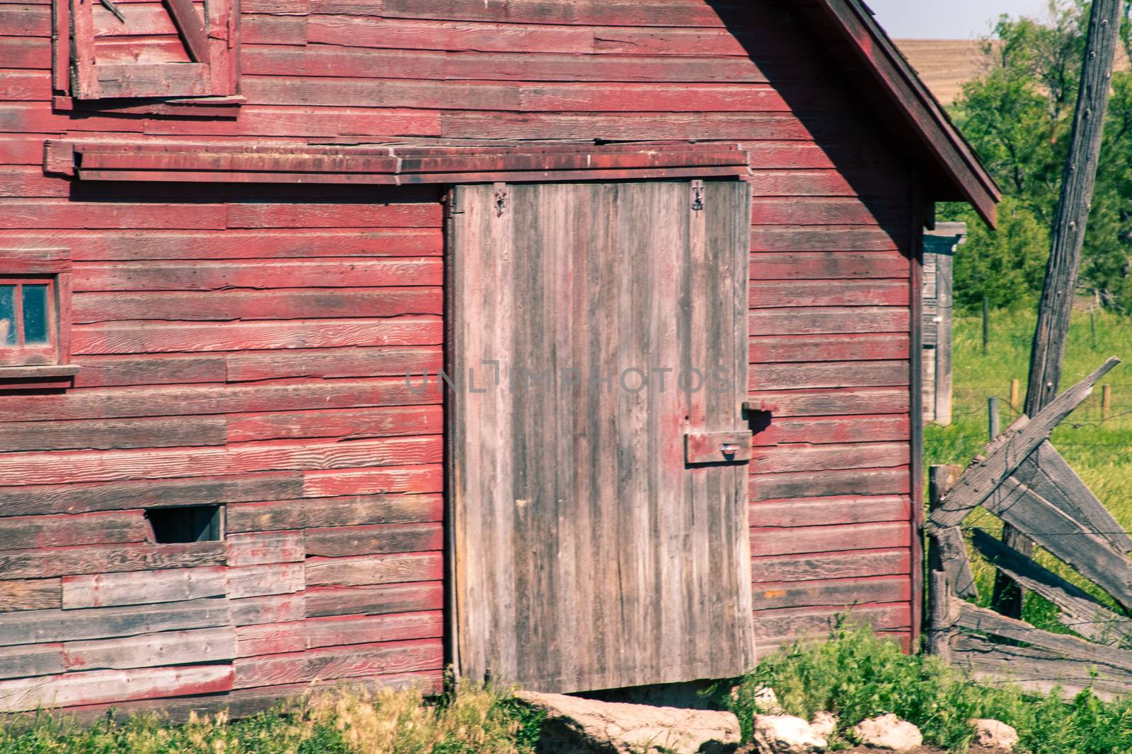  Front of an old abandoned red barn with door and sliding door  by gena_wells