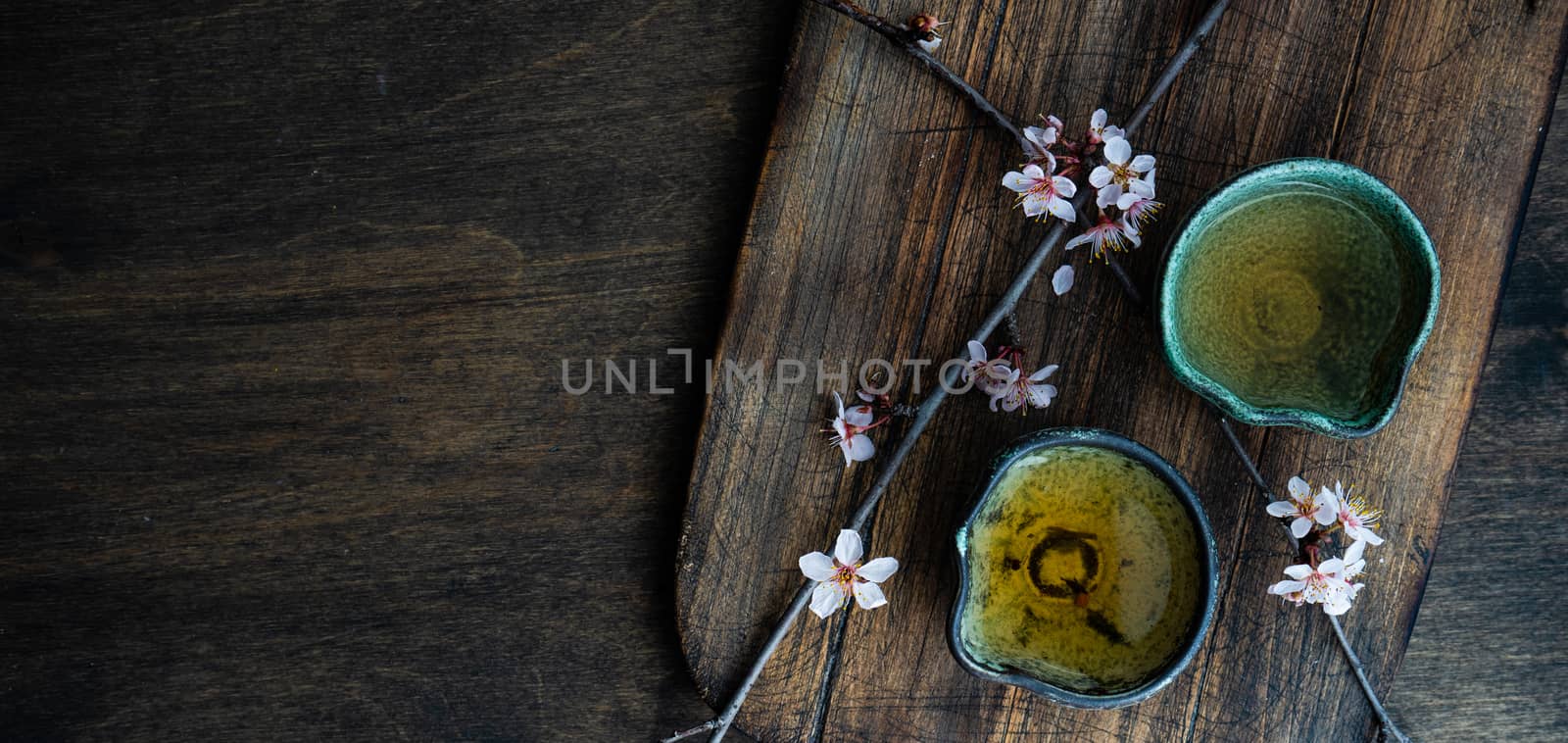 Asian style green tea set and blooming peach tree branch on wooden table with copy space