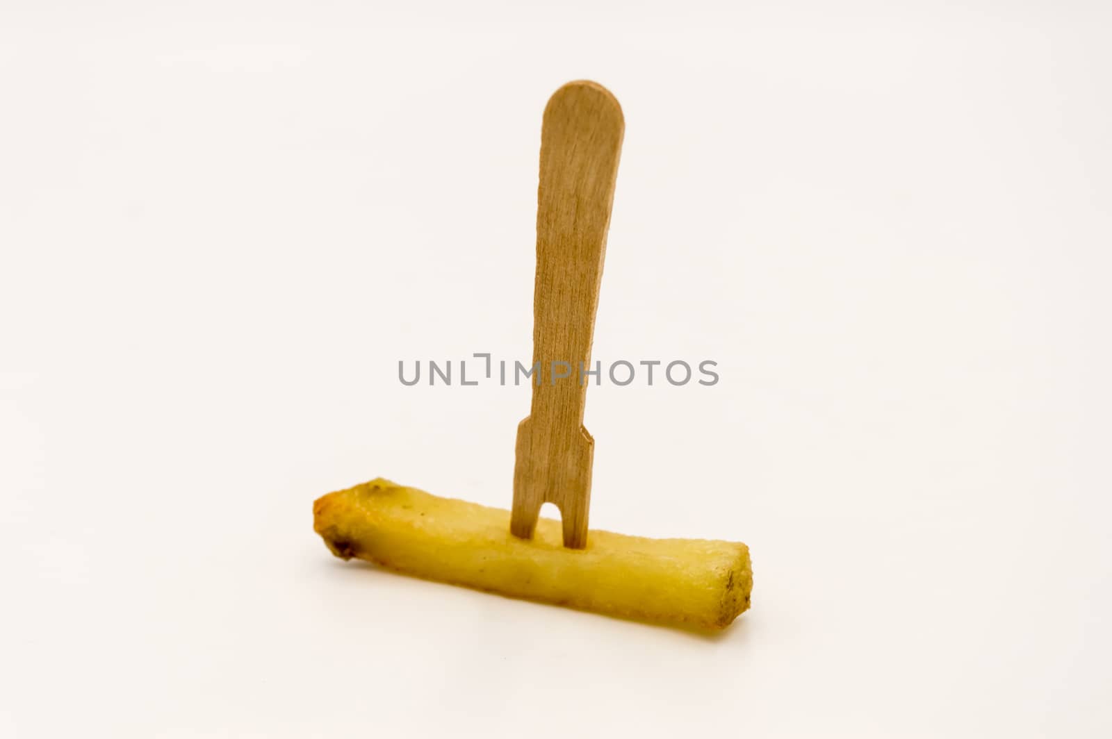 Wooden fries fork on a baked french fries on a white background