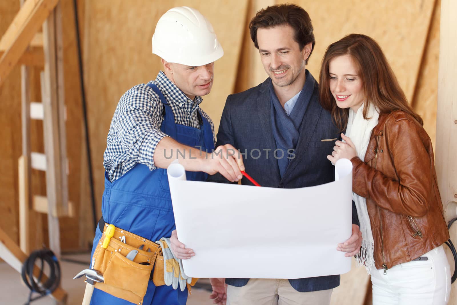 Foreman showing house design construction plan to a happy young couple new house real estate concept