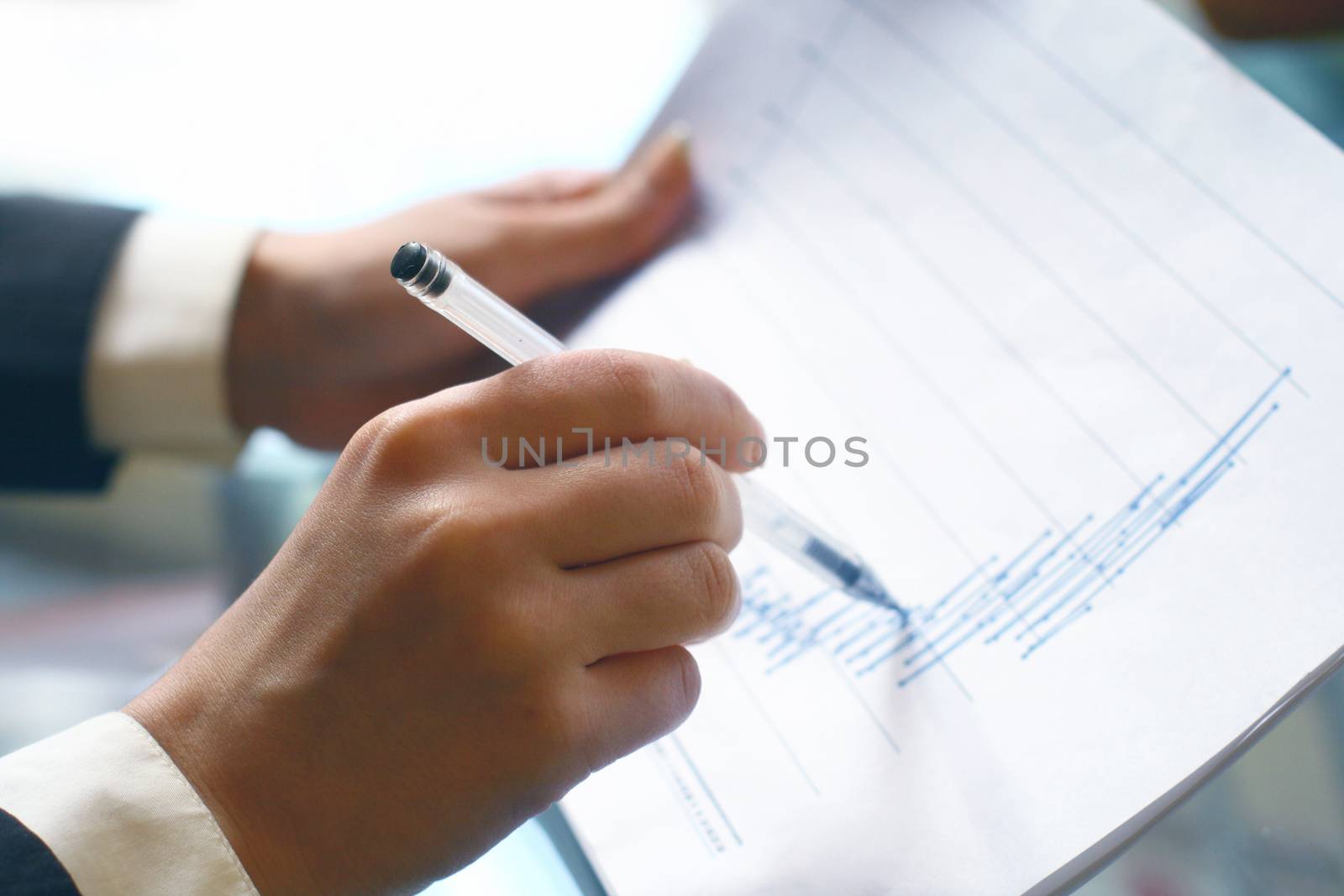 read the graph in financial report, hand pointing at graph with pen