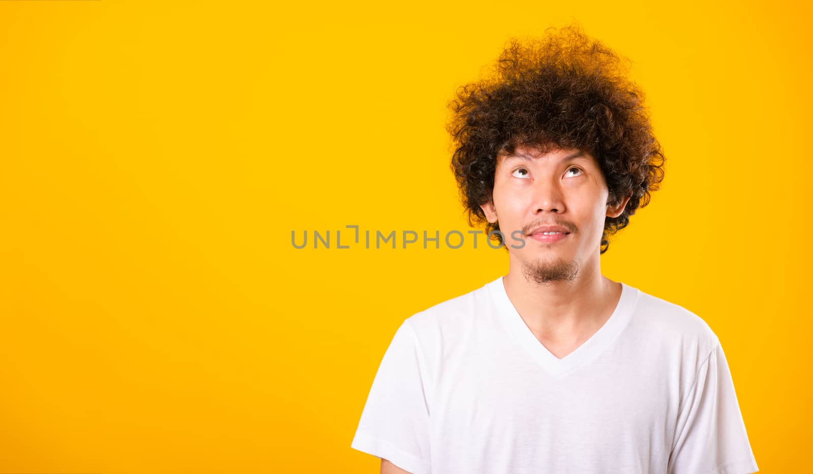 Asian handsome man with curly hair looking up see he hair isolate on yellow background with copy space for text